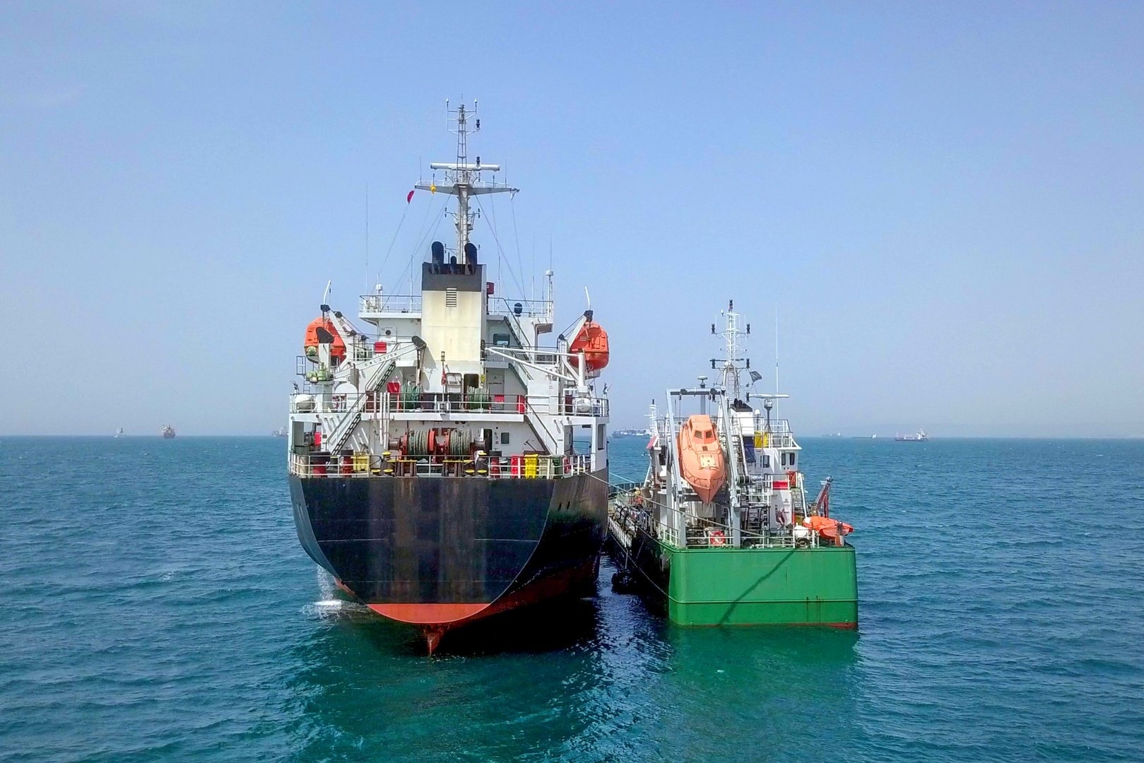 Tug boats drag Oil ship tanker park to port for transfer crude oil to oil refinery.