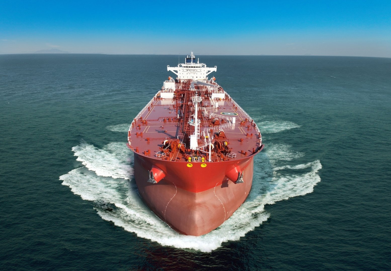 A close-up front view of an oil and chemical carrier causing a spray as it navigates the ocean.